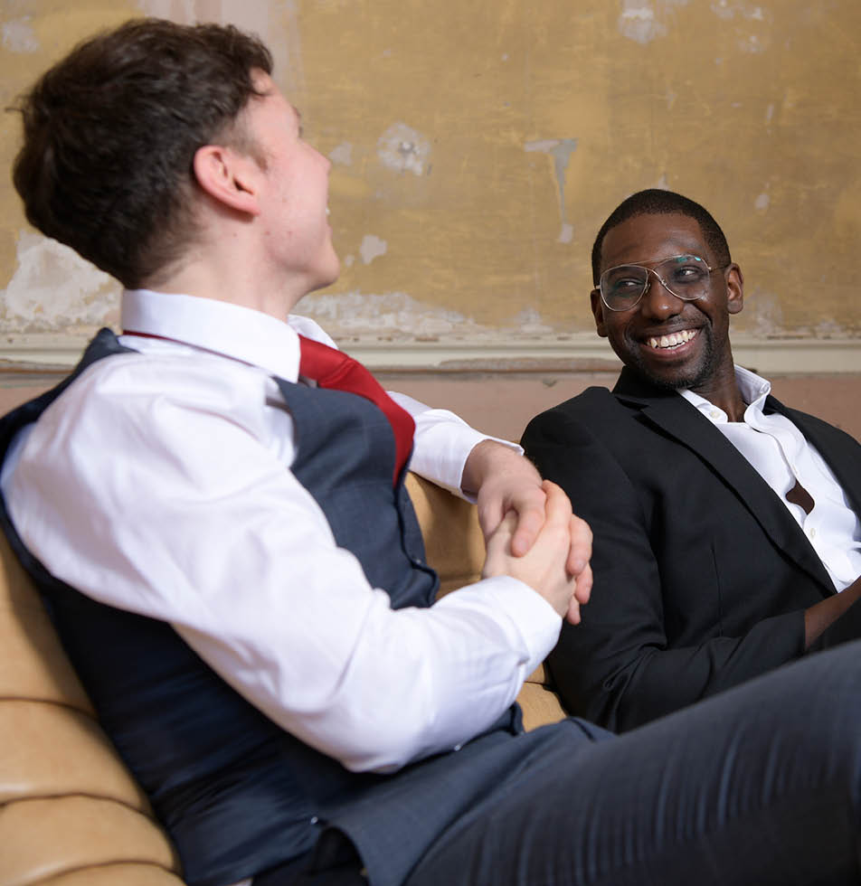 Two people smiling sat on a sofa